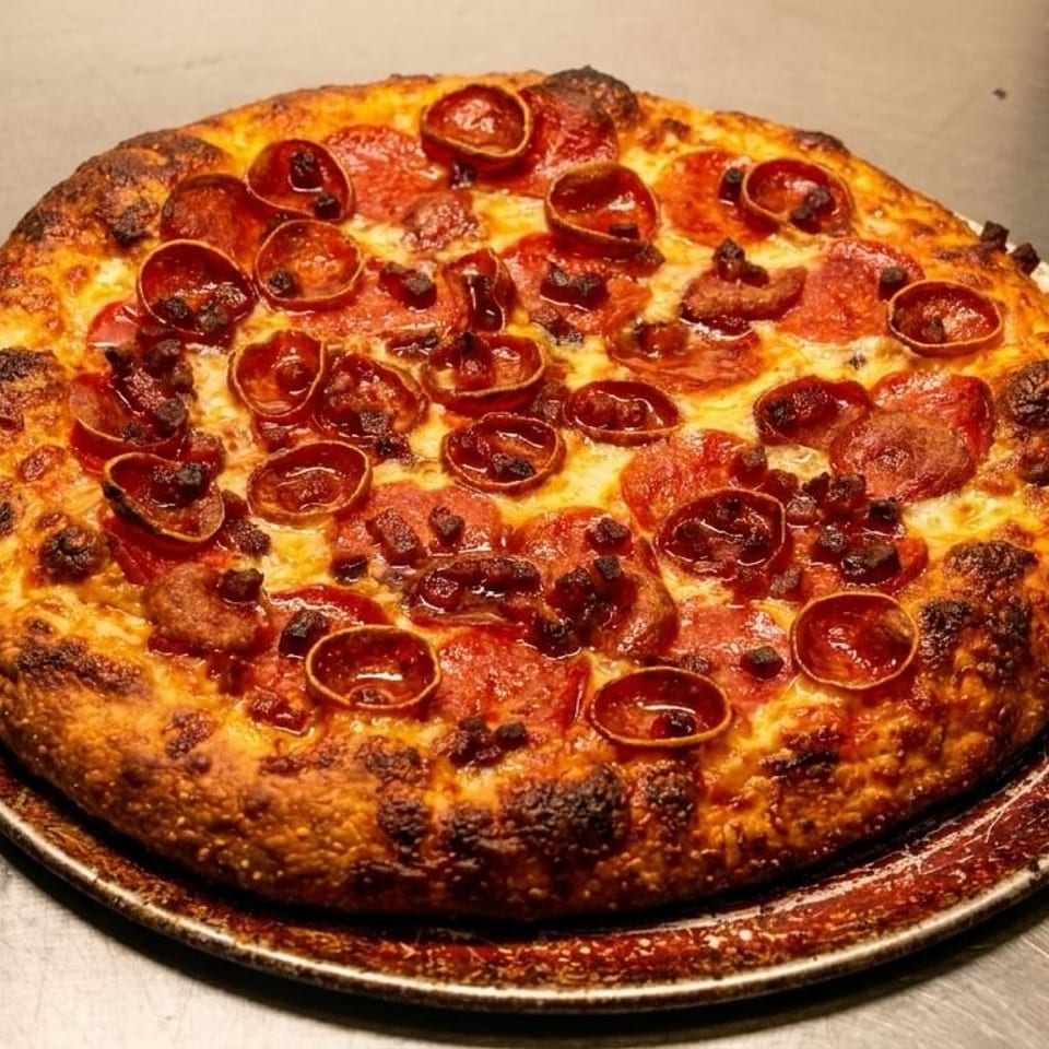 A freshly baked pepperoni and sausage pizza with a crispy crust on a metal pan.